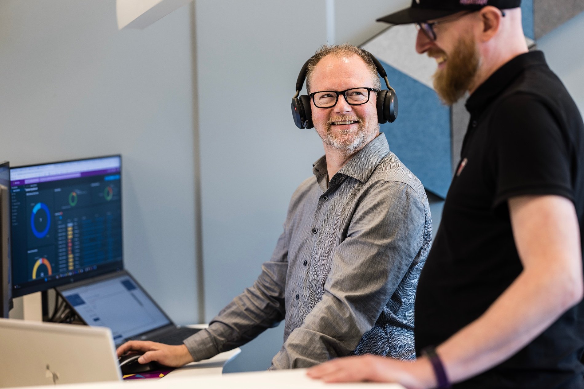 To menn smiler foran PC-skjerm